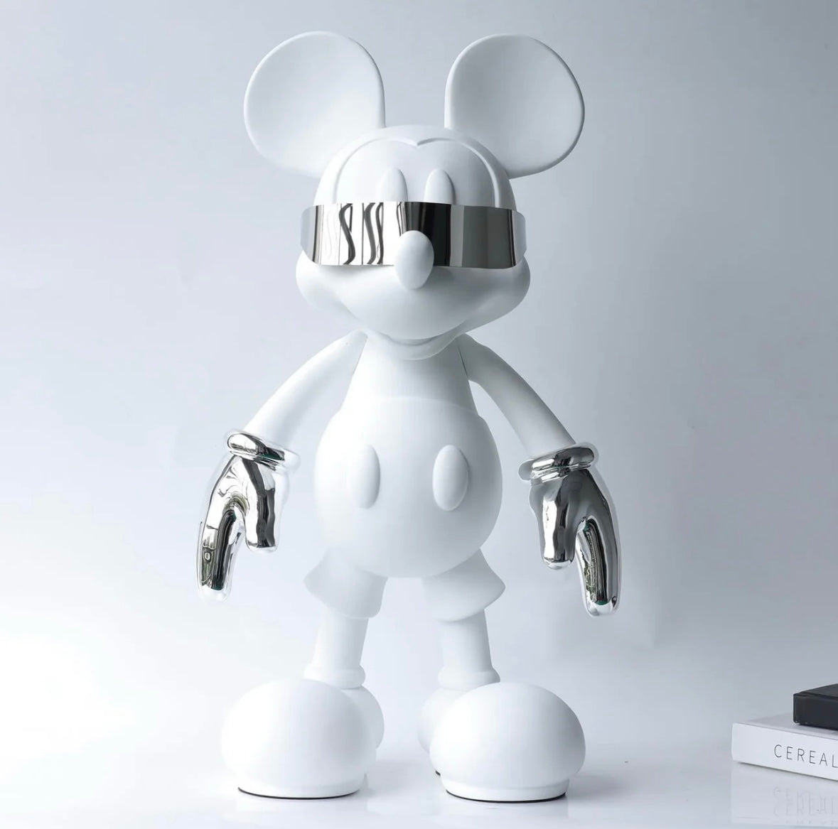 En slimmad vit Mickey Mouse-figur med glänsande silvriga handskar, som förenar klassisk lekfullhet med modern elegans.