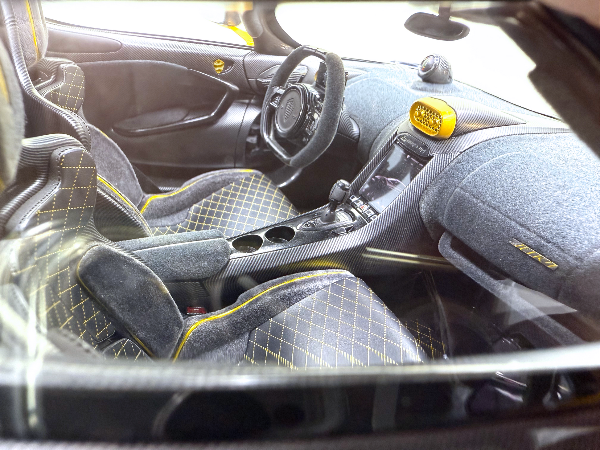 Närbild av kupén i Koenigsegg Jesko Carbon Fury Edition med gul-accenterade racingsäten, kolfiberinstrumentpanel och ett högpresterande rattarrangemang.