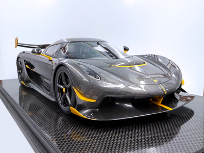 Vinklad sidovy av Koenigsegg Jesko – Carbon Fury Edition i skala 1:8 som visar exponerad kolfiberkaross, gula linjedetaljer och aggressiv aerodynamik från front till bak.