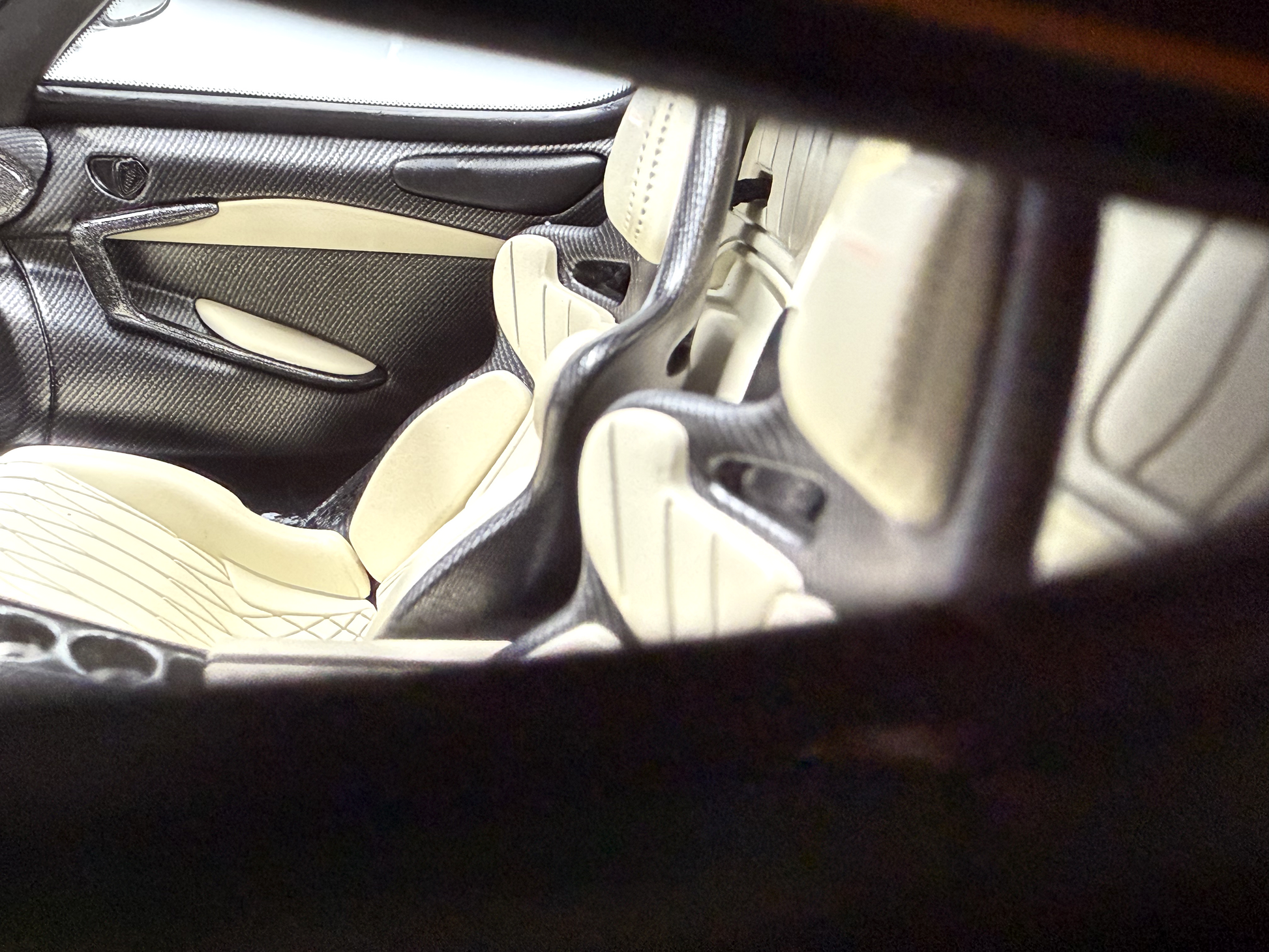 Närbild av en Koenigsegg Jesko-interiör med slanka kolfiberpaneler och två stilrena gräddfärgade racerstolar.