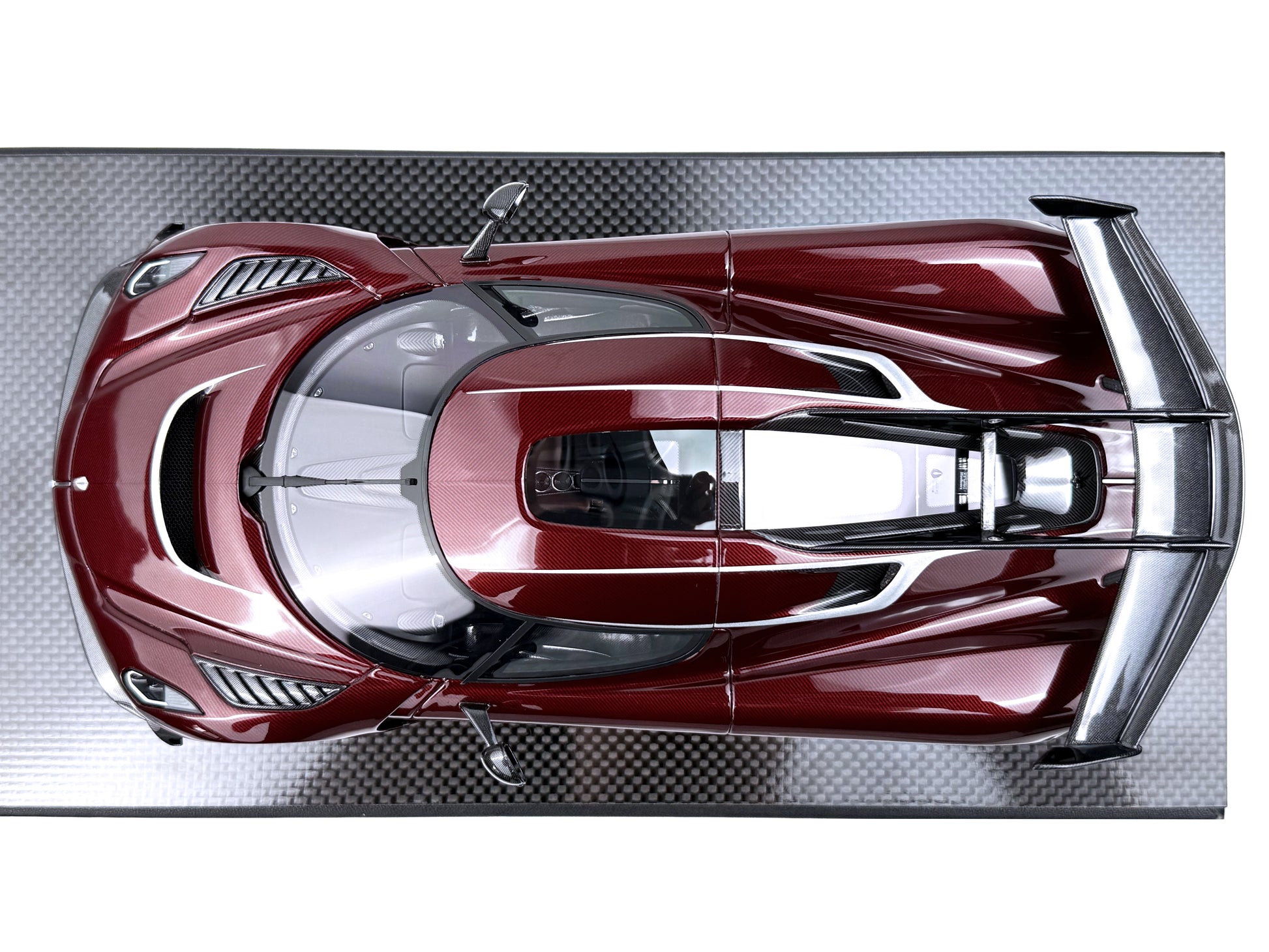Övergripande vy snett ovanifrån till höger av Koenigsegg Jesko Red Tinted Carbon Edition 1:18, som visar den slanka kolfiberkarossen och taklinjen.