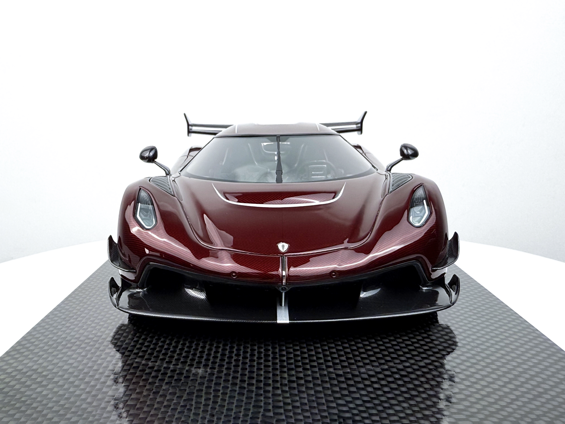 Framifrån vy av Koenigsegg Jesko Red Tinted Carbon Edition 1:18, med aggressiva strålkastare och skulpterad front.
