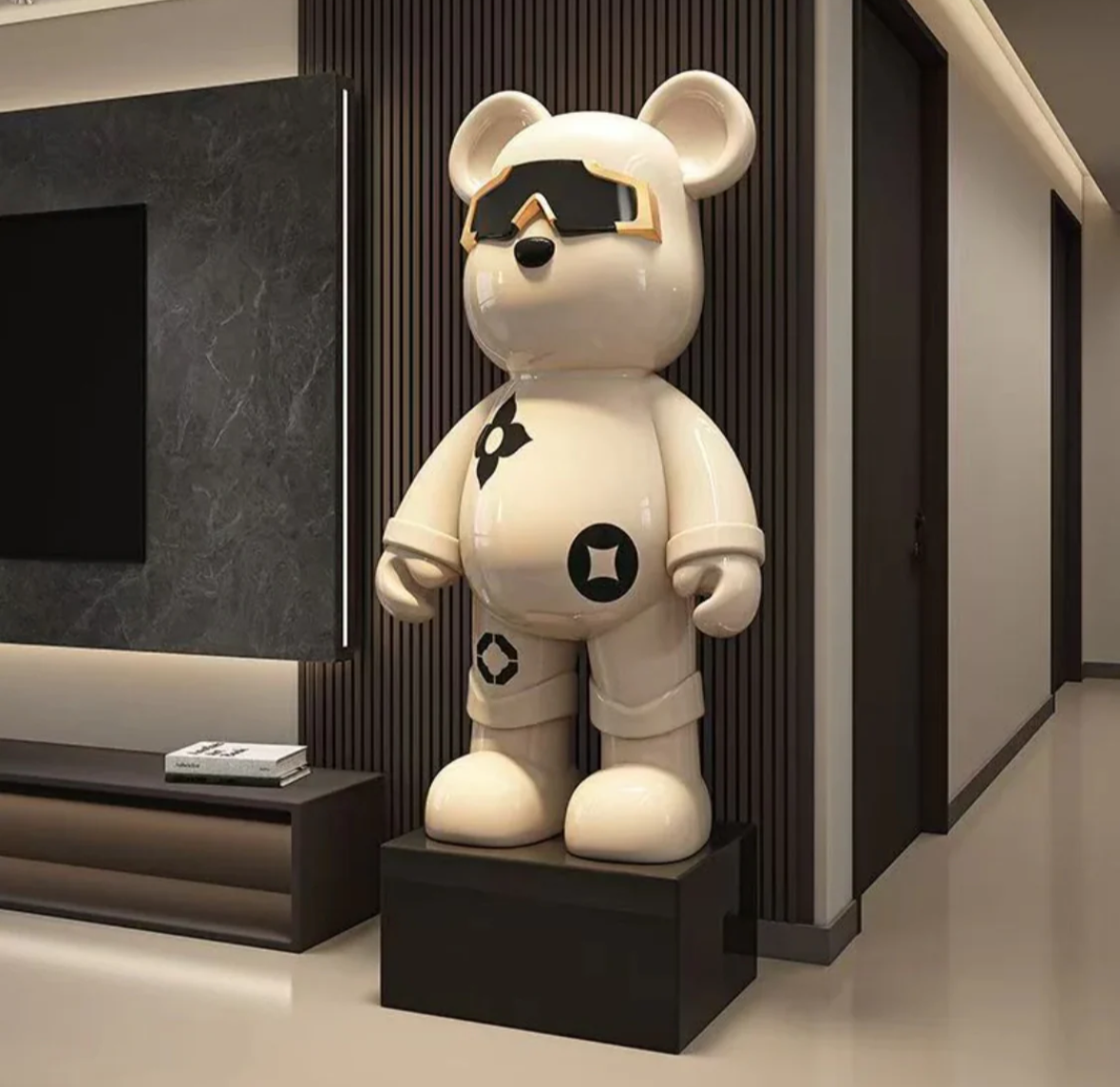 Vit Astro Bear-staty med svarta symboler och glansig visir, stående på en svart piedestal.